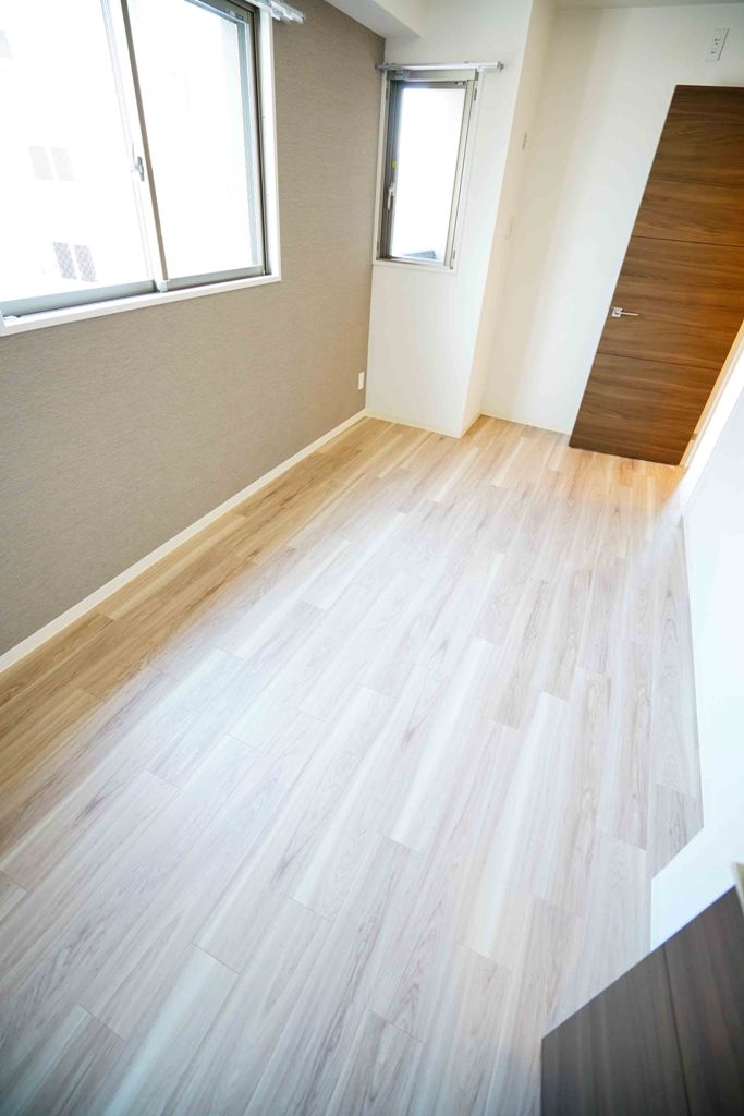 Gate Court Higashimikuniの東面窓付き6.5帖洋室:フローリングは木目調のベージュ、クロスはグレイ、建具はダークブラウン